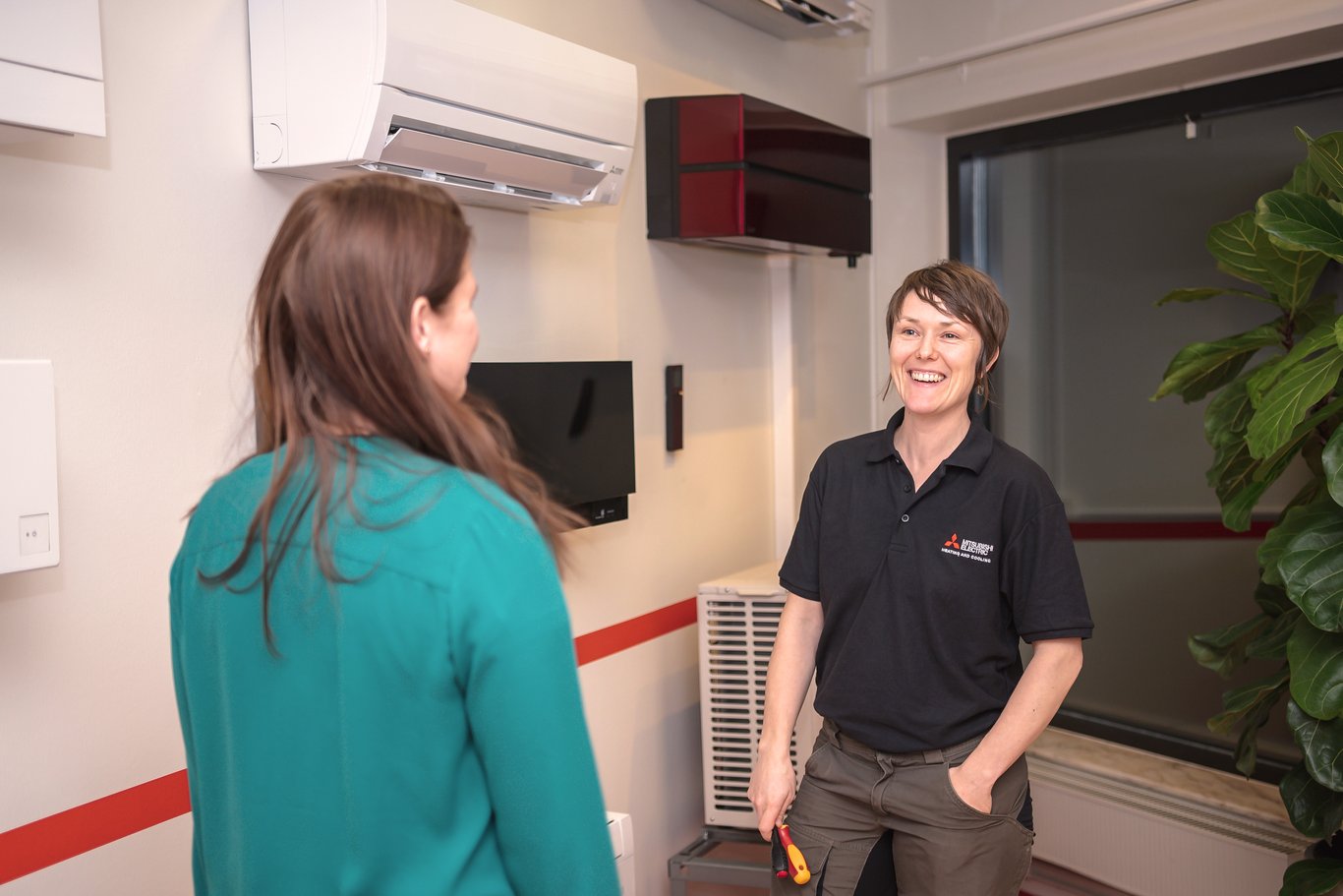 En Mitsubishi Electric tekniker samtalar med en kund framför en installerad luftkonditioneringsenhet. Mitsubishi Electric har en stark lokal närvaro i Sverige med över 30 auktoriserade återförsäljare och kontor i Göteborg, Lund och Stockholm, som hjälper både villaägare och kommersiella kunder.